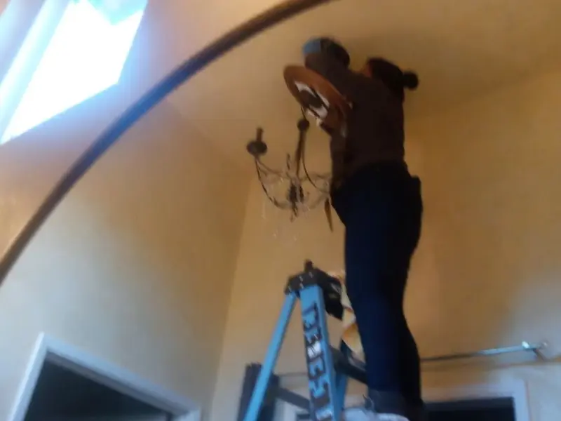 Electrician installing a chandelier in a Clanton residence